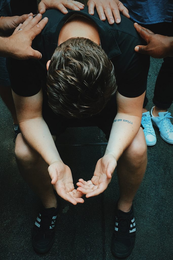 young man receiving prayer from a group of friends