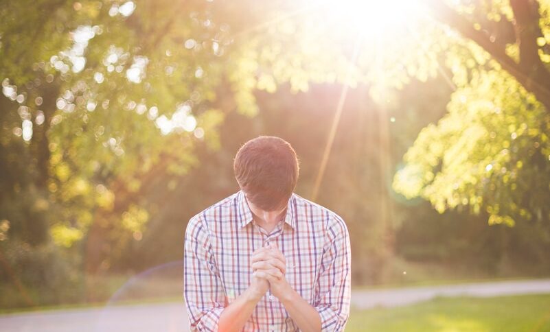 photo of man kneeling on grass near tree